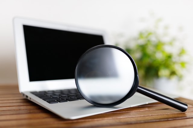 虫眼鏡が置かれたパソコン