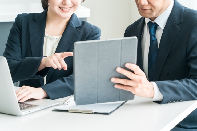 タブレットを見ながら打ち合わせをする男女