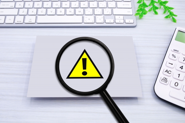 虫眼鏡で拡大された注意マーク